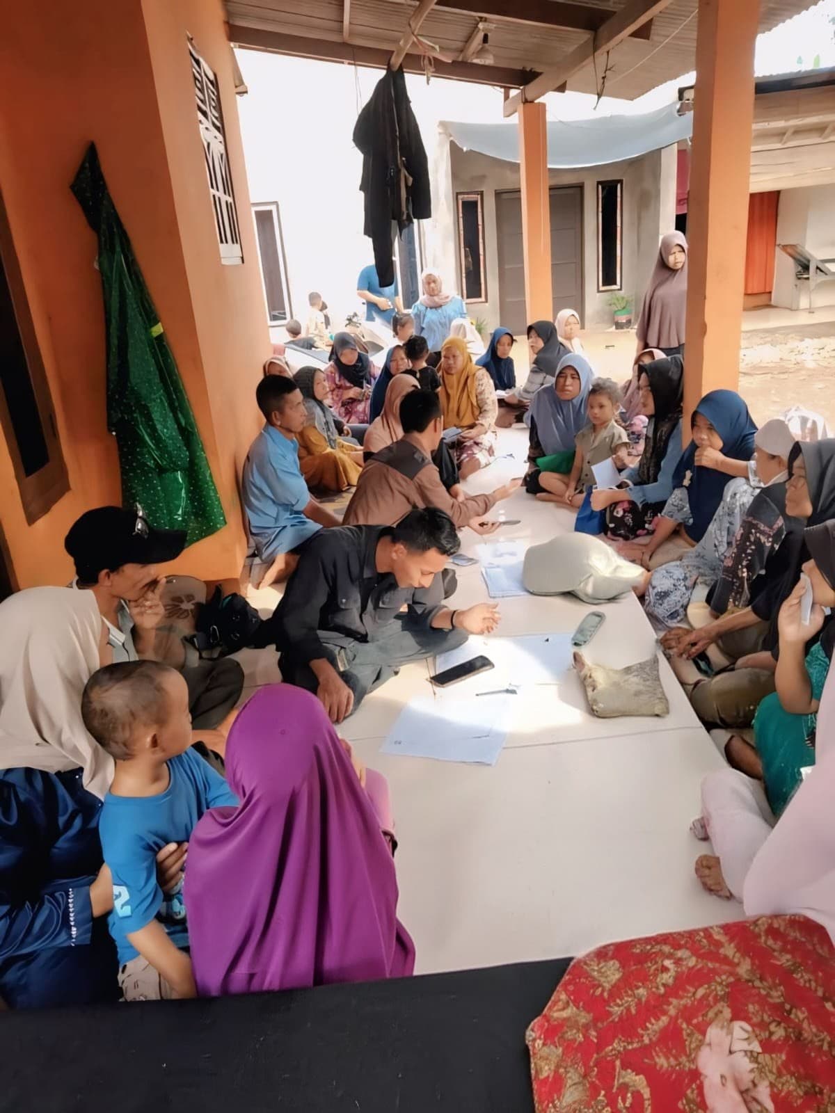 Puluhan warga duduk lesehan mengikuti sosialisasi program JKN bersama tim lapangan.