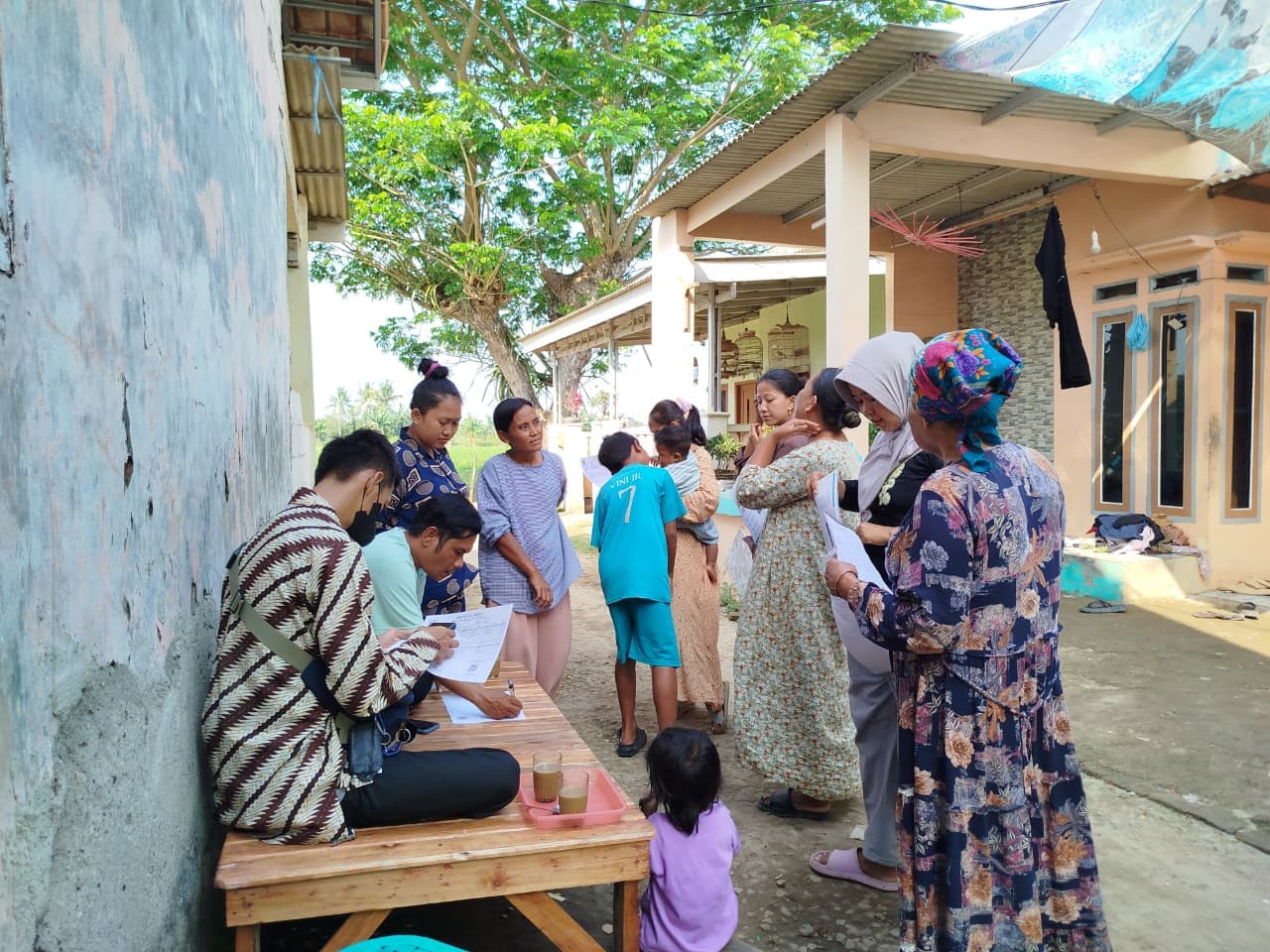 Tim lapangan S1-Mitra mendata calon peserta di meja pendaftaran sementara, dengan warga mengantre membawa formulir.